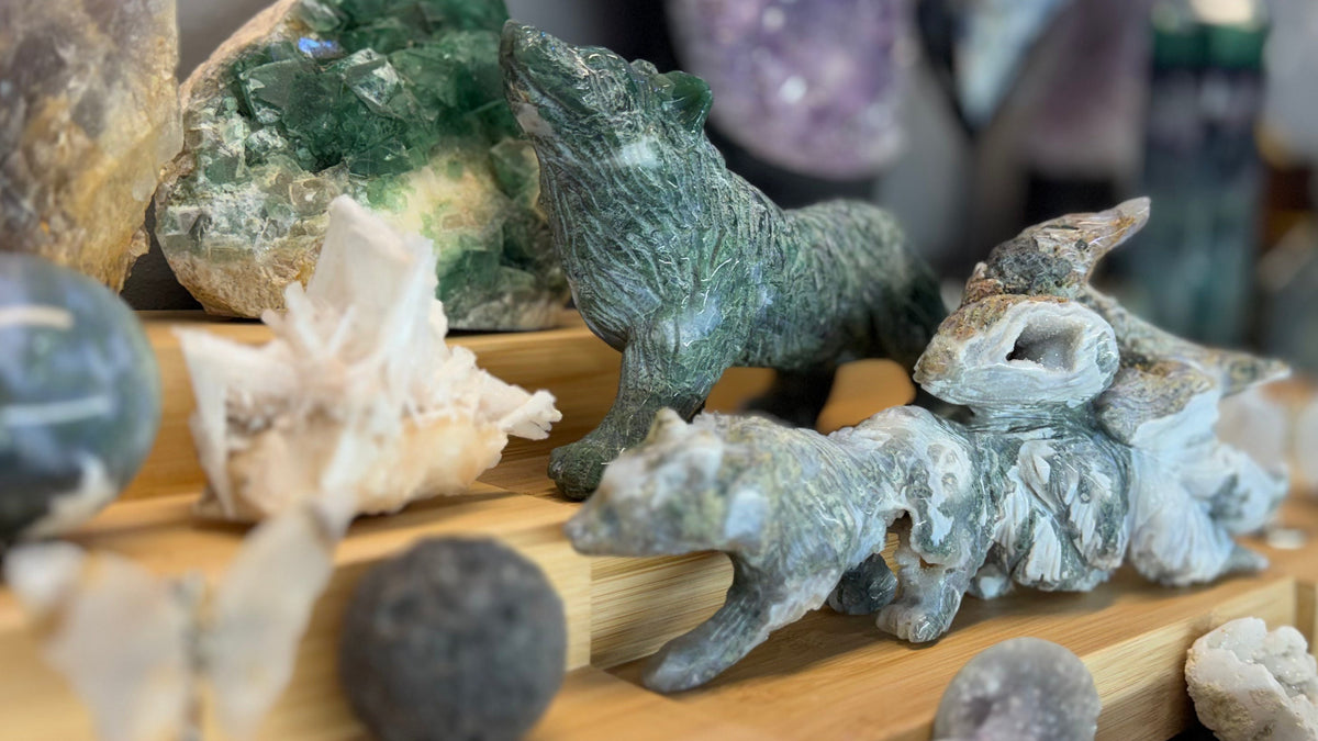 Crystals on display at Celestial Crystal Haven: a carved moss agate wolf with fluorite and druzy crystals